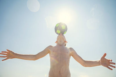 Low angle view of shirtless man against sky on sunny day