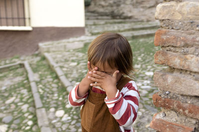 Portrait of girl standing against stone wall