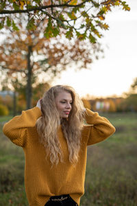 Portrait of a young woman standing against tree