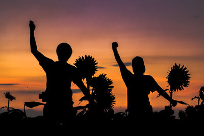 Silhouette people standing against sky during sunset