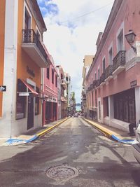 Empty road amidst buildings against sky