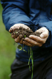 Midsection of man holding soil while standing at farm