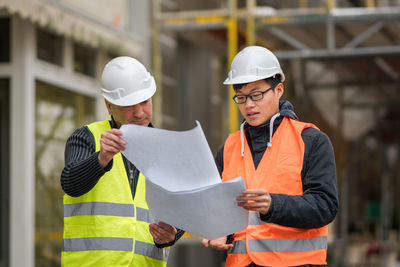 Engineers discussing while standing at construction site