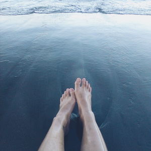 Low section of woman on shore at beach