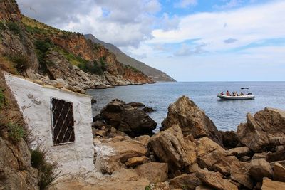 Scenic view of rocks by sea against sky