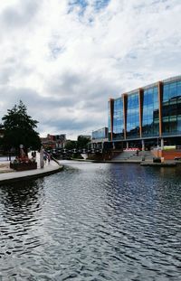 City at waterfront against cloudy sky