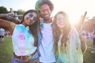 Portrait of happy friends at carnival against bright sky