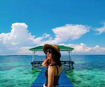 Full length of young woman standing in sea against sky