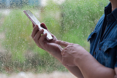 Midsection of man holding mobile phone