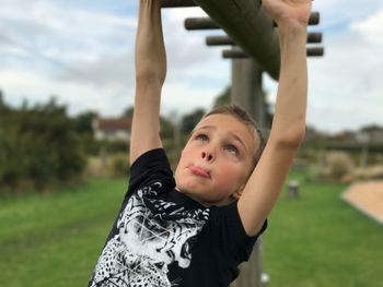 Portrait of young woman with arms raised standing against sky