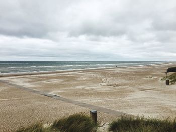 Scenic view of beach against cloudy sky