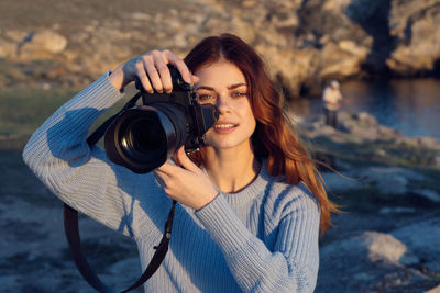 Portrait of young woman photographing camera