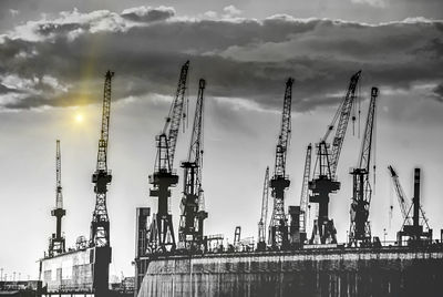 Low angle view of crane against cloudy sky
