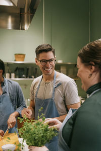 Happy male student talking to female friend during cooking class in kitchen