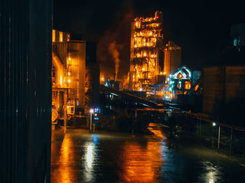 The view of the cement factory building lights at night after the rain.