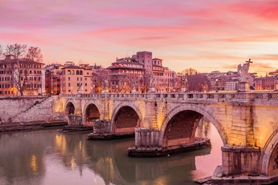 Arch bridge over river during sunset