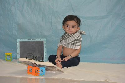 Portrait of cute boy sitting on bed at home