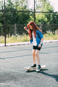 Cute teen girl rides a skateboard on a sports field