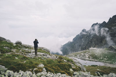 Rear view of man standing on mountain against sky