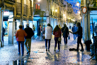 People walking on snow covered city at night