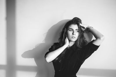 Thoughtful young woman standing against wall