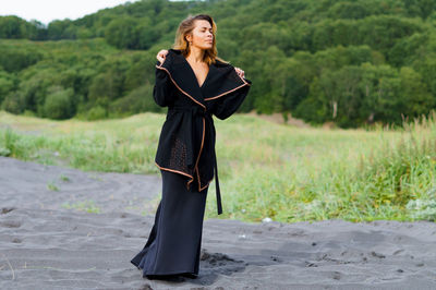 Mid adult woman wearing black dress at beach