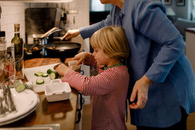 Boy helping grandmother in cutting vegetable at home