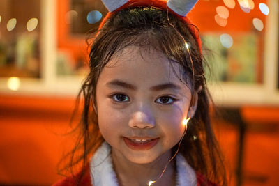 Close-up portrait of cute girl with string lights