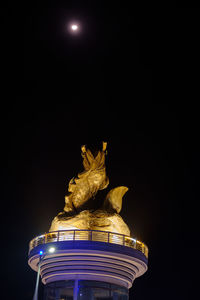 Low angle view of illuminated statue against sky at night