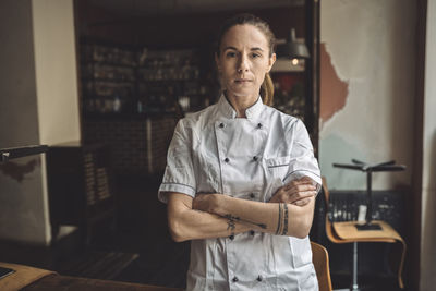 Portrait of chef with arms crossed standing in restaurant