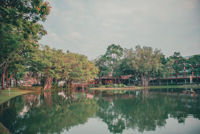 Scenic view of lake by trees and building against sky