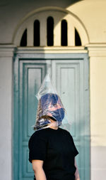 Medium close up portrait of a woman using plastic and a mask to protect herself from covid