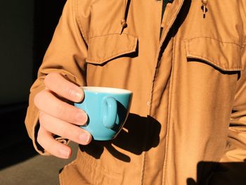 Mid section view of man holding cup of tea