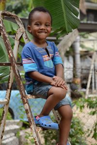 Portrait of boy sitting on rusty ladder