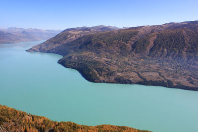 Scenic view of lake and mountains against clear blue sky