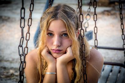 Portrait of beautiful woman on swing at playground