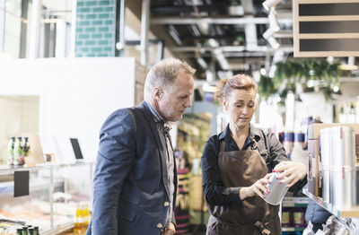 Saleswoman explaining product to man in organic supermarket