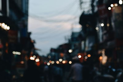 Defocused image of illuminated city against sky at night