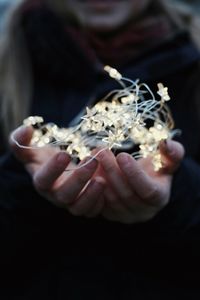 Midsection of man holding illuminated string light