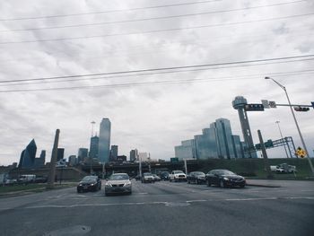 Cars on road against cloudy sky
