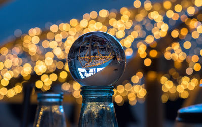 Close-up of crystal ball against illuminated lights in city at night