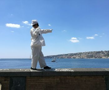 Man standing at beach against blue sky