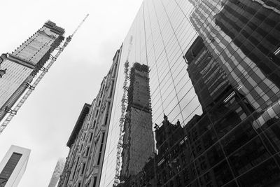 Low angle view of crane and buildings against sky
