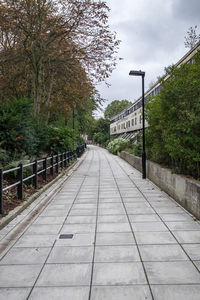 Footbridge over river in city against sky