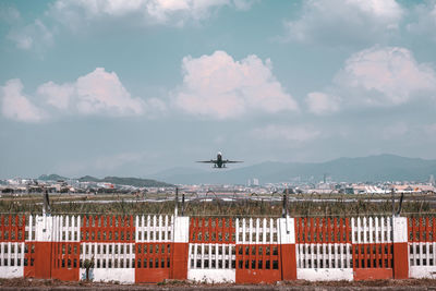 Airplane flying over buildings in city against sky