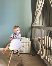 Portrait of boy sitting on chair at home