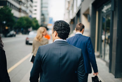 Rear view of people walking on city street