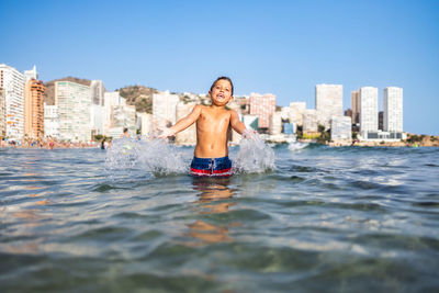 Funny kid spalshing water on an urban beach