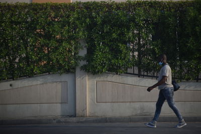 Full length of man standing on footpath by plants