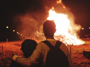 Rear view of man standing against illuminated bonfire